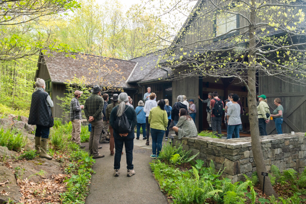 A group of people gather outside a barn. 