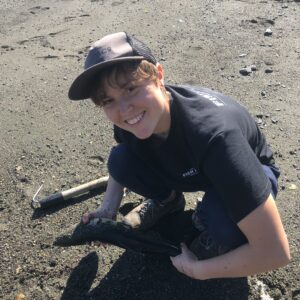 A woman smiles and holds a salmon on a beach. A Q&A with Highstead’s New Conservation Interns